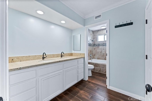 full bathroom featuring toilet, vanity, ornamental molding, and tiled shower / bath