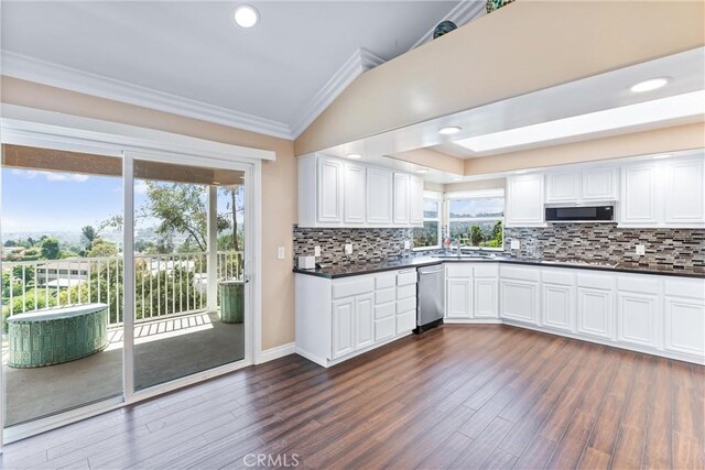 kitchen featuring plenty of natural light, white cabinets, ornamental molding, and vaulted ceiling