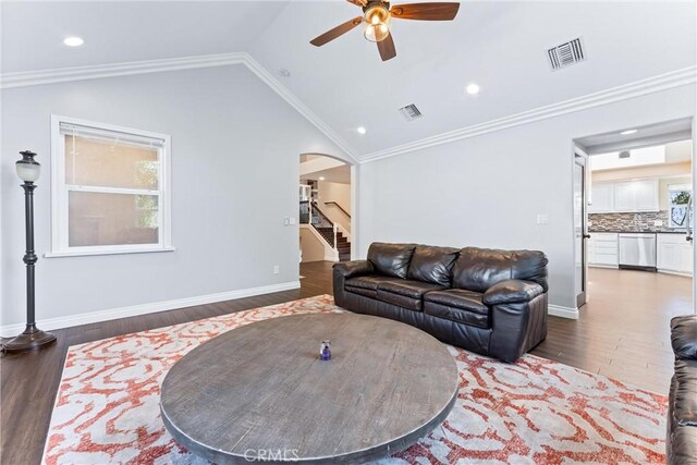 living room with ceiling fan, vaulted ceiling, dark wood-type flooring, and ornamental molding