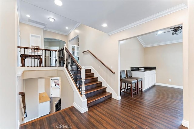 stairs featuring ceiling fan, ornamental molding, and wood-type flooring