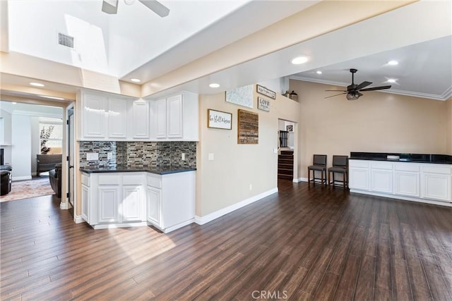 kitchen featuring ceiling fan, dark hardwood / wood-style floors, decorative backsplash, crown molding, and white cabinets