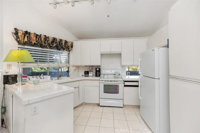 kitchen featuring vaulted ceiling, tile countertops, white appliances, white cabinetry, and a healthy amount of sunlight