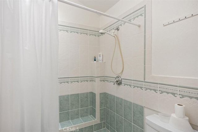 bathroom featuring walk in shower, tile walls, and toilet