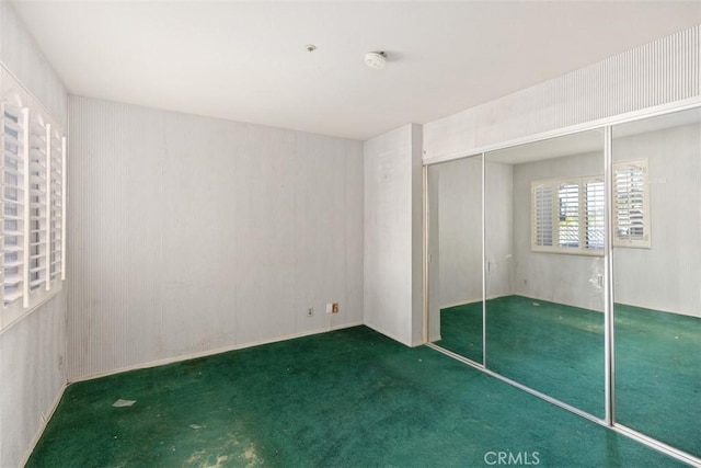 unfurnished bedroom featuring dark carpet and a closet