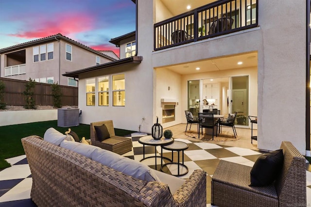 patio terrace at dusk with an outdoor living space with a fireplace