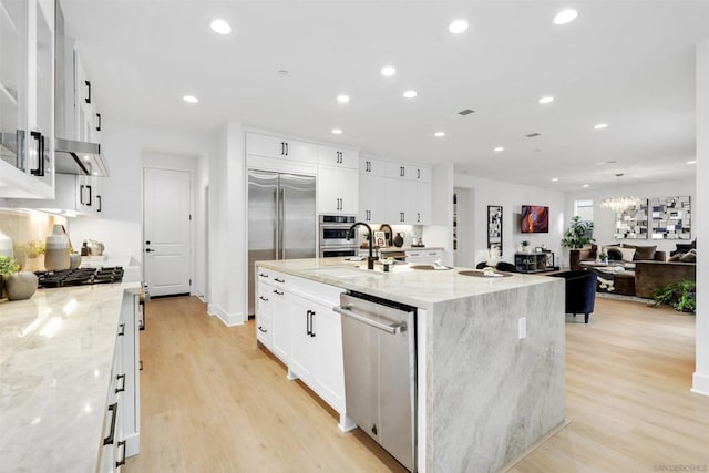 kitchen with light stone countertops, a spacious island, white cabinets, and appliances with stainless steel finishes