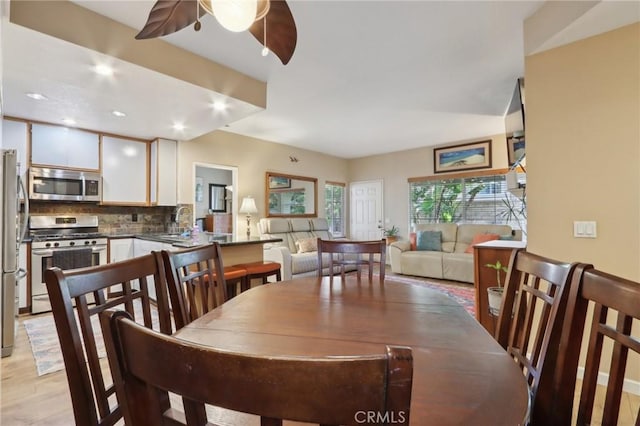 dining space featuring ceiling fan, light wood-type flooring, and sink