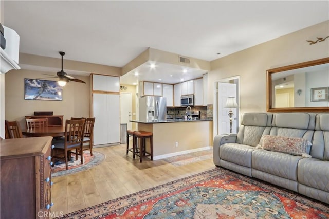 living room with ceiling fan, sink, and light wood-type flooring