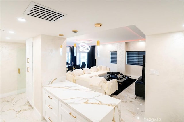 kitchen featuring pendant lighting, light stone countertops, and white cabinetry