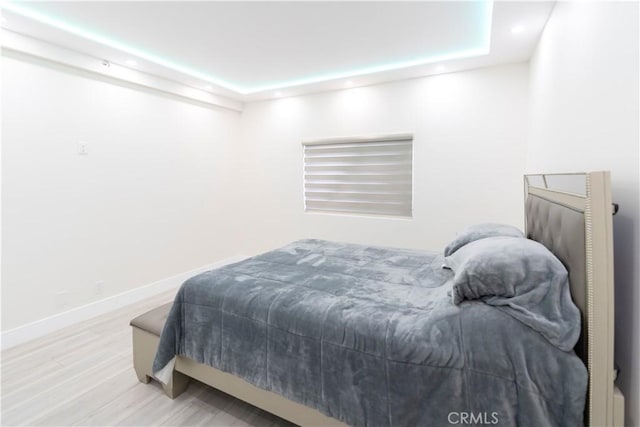 bedroom featuring a tray ceiling and light hardwood / wood-style flooring