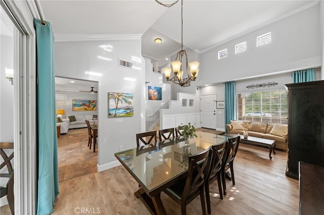 dining area featuring ceiling fan with notable chandelier, vaulted ceiling, ornamental molding, and light wood-type flooring