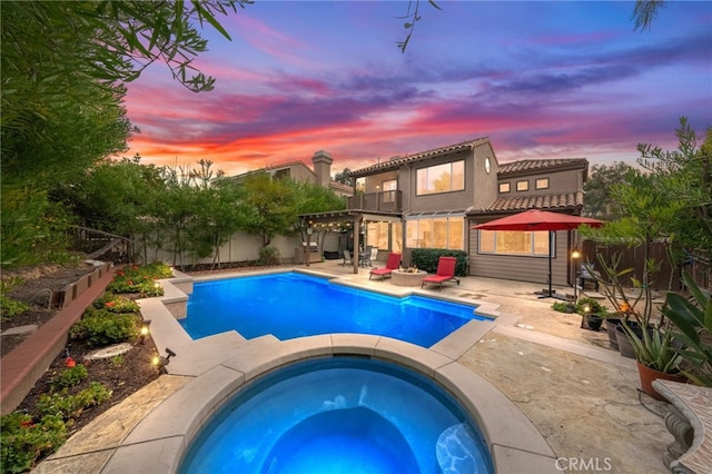 pool at dusk with a pergola, a patio, and an in ground hot tub