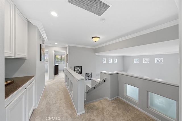 interior space featuring crown molding, white cabinets, and light carpet