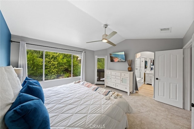 bedroom with vaulted ceiling, ceiling fan, connected bathroom, and light colored carpet