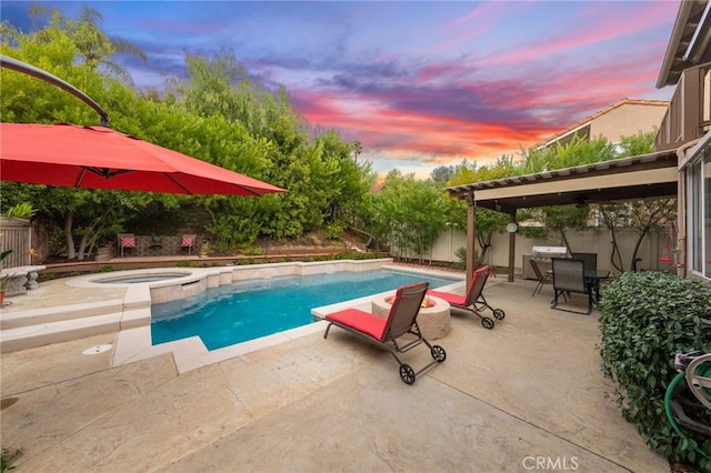 pool at dusk featuring a patio and an in ground hot tub