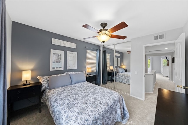 bedroom featuring ceiling fan, light colored carpet, and a closet