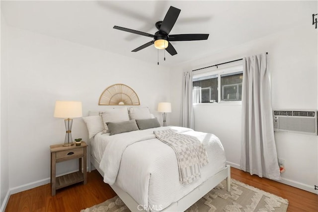 bedroom with a wall unit AC, ceiling fan, and hardwood / wood-style floors