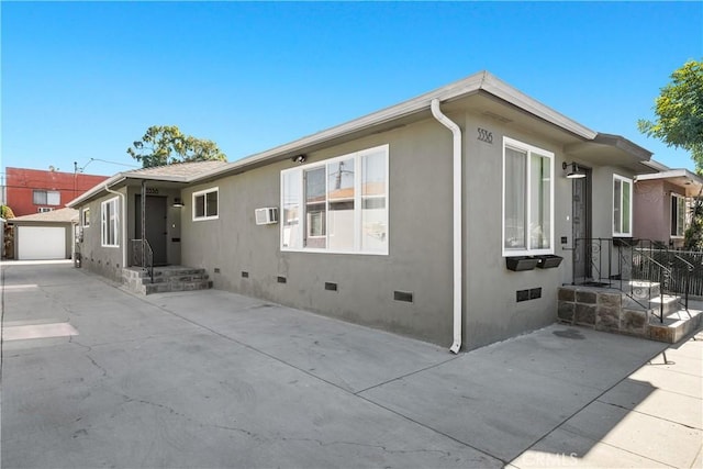 view of home's exterior featuring a garage, an outbuilding, and a wall mounted air conditioner