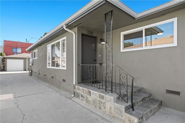 5536 Linden Ave, Long Beach, CA 90805 - view of exterior entry featuring a garage, stucco siding, crawl space, visible vents, and driveway