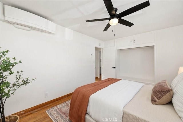 bedroom with ceiling fan, hardwood / wood-style flooring, a closet, and a wall mounted air conditioner