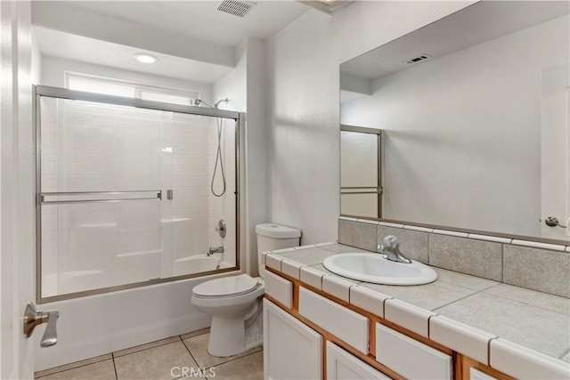 full bathroom with bath / shower combo with glass door, vanity, tile patterned floors, and toilet