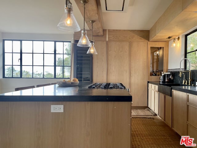 kitchen with stainless steel gas cooktop, a center island, sink, and pendant lighting