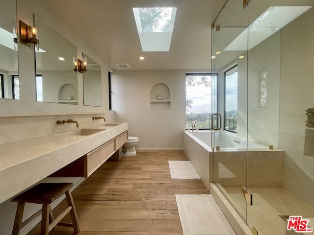 full bathroom with separate shower and tub, vanity, toilet, hardwood / wood-style floors, and a skylight