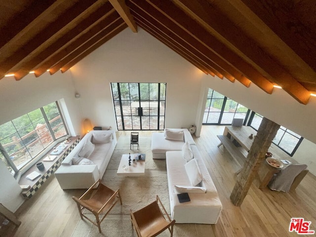 living room with high vaulted ceiling, light hardwood / wood-style floors, and beam ceiling