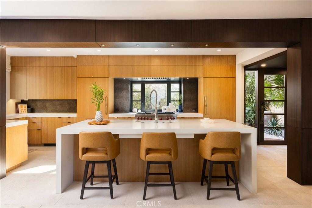 kitchen with a spacious island, sink, a breakfast bar, and tasteful backsplash