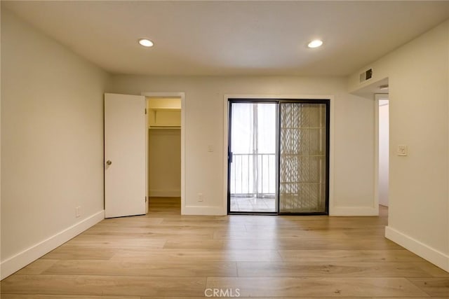 unfurnished bedroom featuring light wood-type flooring, a closet, and a spacious closet