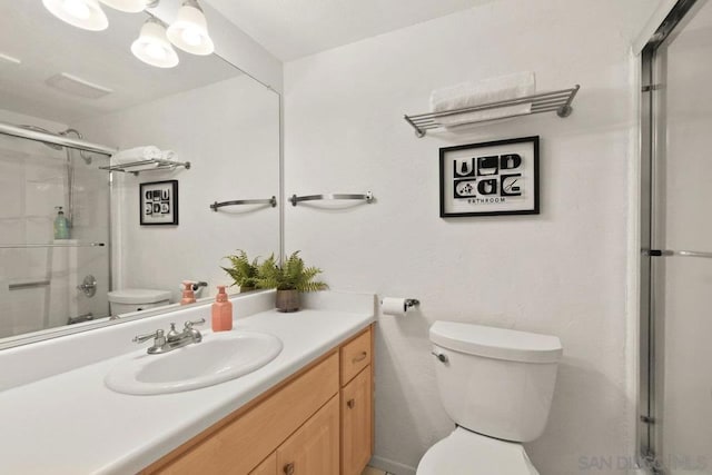 bathroom with an enclosed shower, vanity, and toilet