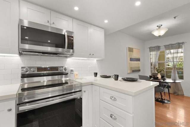 kitchen featuring white cabinets, appliances with stainless steel finishes, tasteful backsplash, and light wood-type flooring