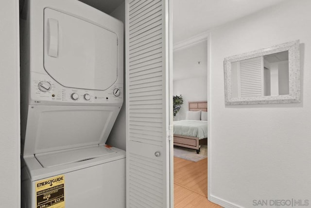 clothes washing area featuring hardwood / wood-style flooring and stacked washer and dryer