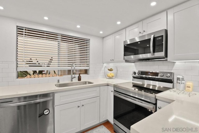 kitchen featuring decorative backsplash, appliances with stainless steel finishes, sink, and white cabinetry