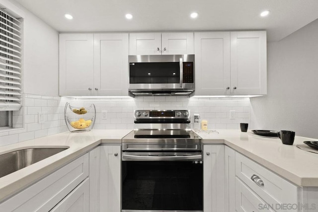 kitchen with backsplash, white cabinets, and stainless steel appliances