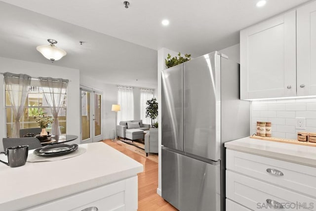 kitchen featuring white cabinetry, decorative backsplash, and stainless steel fridge