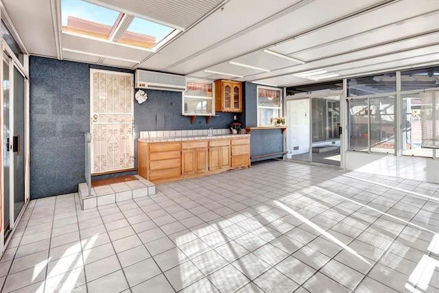 kitchen featuring light tile patterned floors, a skylight, a wall mounted AC, and tile counters