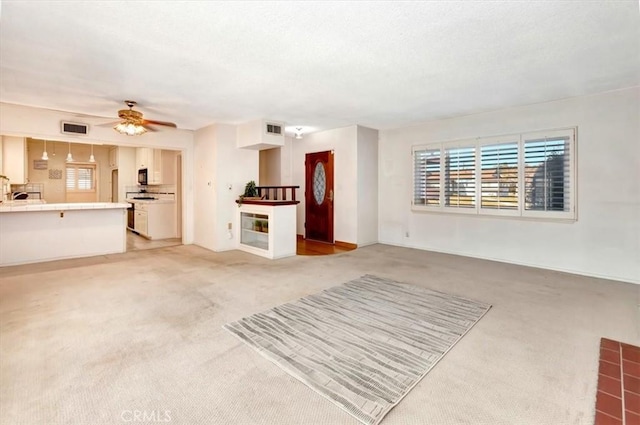 unfurnished living room featuring ceiling fan and light colored carpet