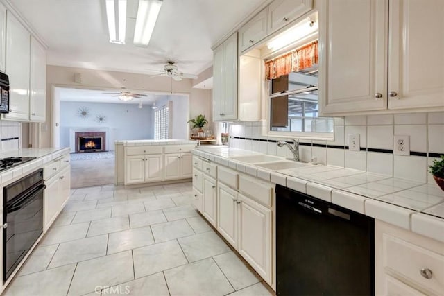 kitchen featuring tasteful backsplash, black appliances, sink, white cabinetry, and tile counters