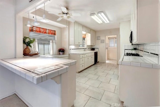 kitchen featuring tile counters, white cabinets, kitchen peninsula, and black appliances