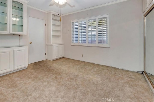 unfurnished bedroom with ceiling fan, light colored carpet, and crown molding