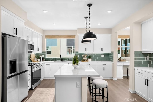 kitchen with appliances with stainless steel finishes, white cabinets, and a center island