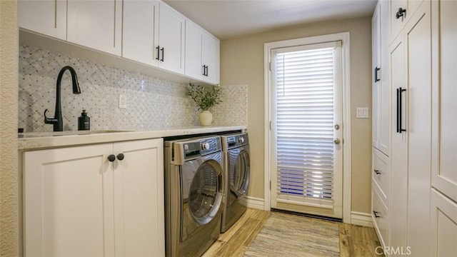 washroom featuring cabinets, light hardwood / wood-style floors, independent washer and dryer, and sink