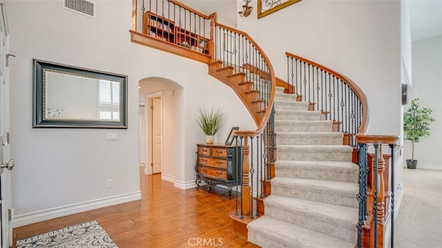 staircase with a towering ceiling and hardwood / wood-style floors