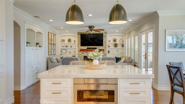 kitchen featuring ceiling fan, a kitchen island, hanging light fixtures, white cabinets, and built in shelves