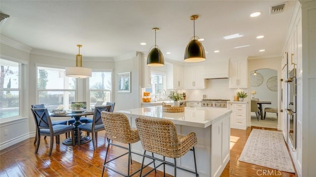 kitchen with white cabinetry, hardwood / wood-style flooring, hanging light fixtures, and a center island