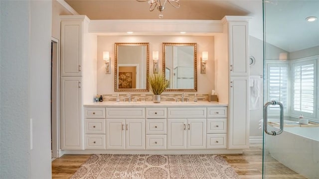 bathroom featuring lofted ceiling, wood-type flooring, vanity, backsplash, and a washtub