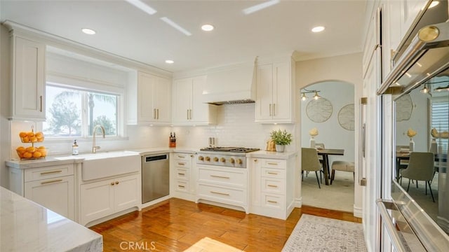 kitchen with decorative backsplash, sink, appliances with stainless steel finishes, custom range hood, and white cabinets