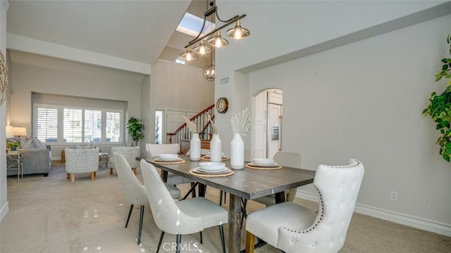 carpeted dining area featuring a towering ceiling