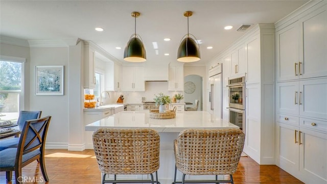 kitchen featuring decorative light fixtures, sink, white cabinetry, and a kitchen island